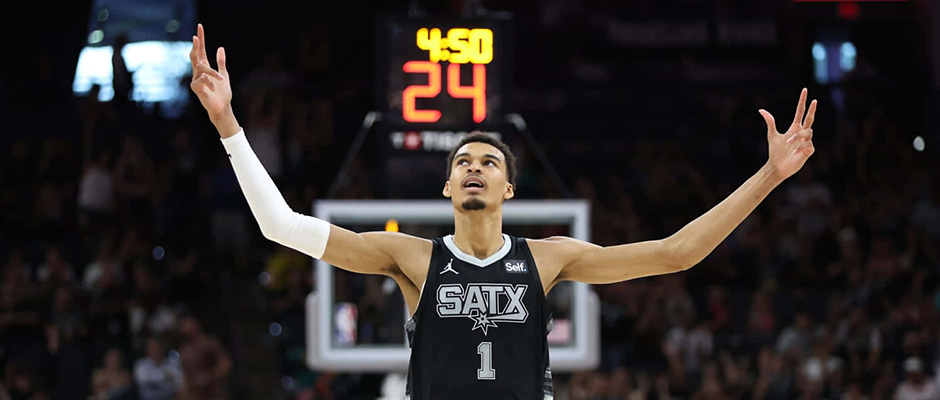 victor-wembanyama-basketball-cards Victor Wembanyama with his hands raised up at a basketball game
